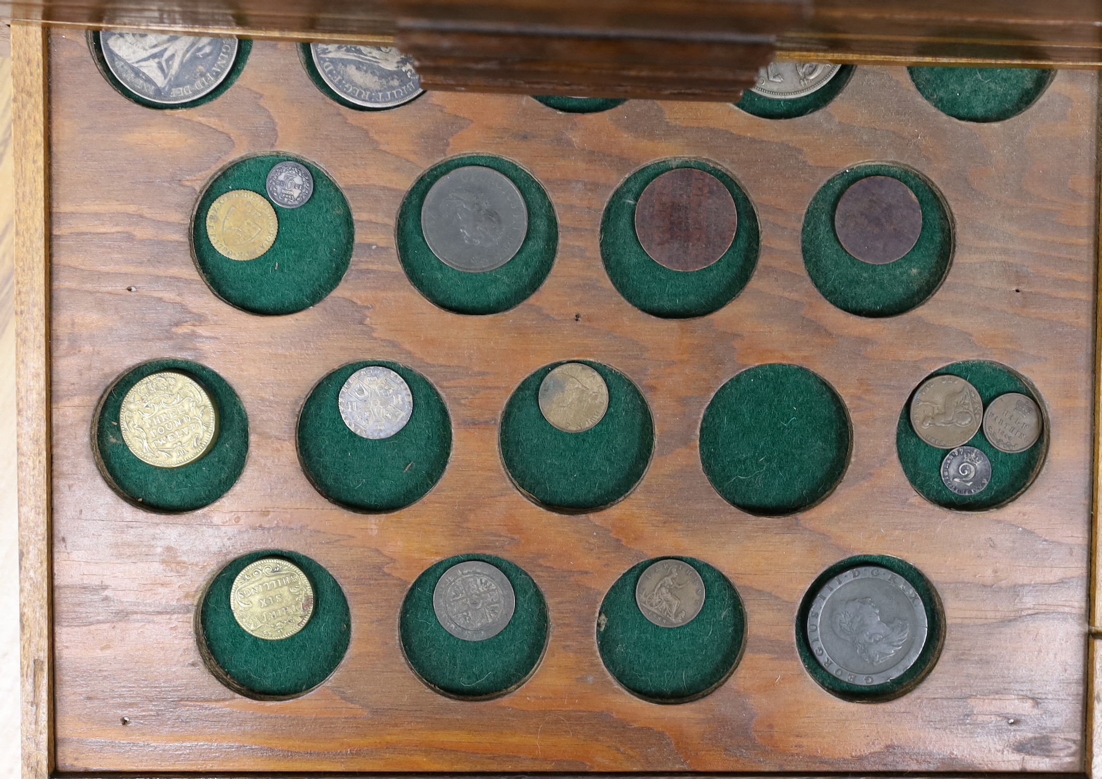 A collection of mixed coinage in a collectors cabinet, 27cm tall